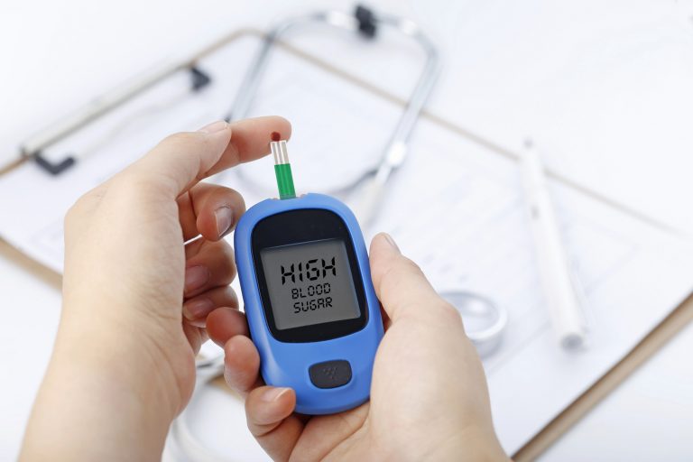 Person holding a blood glucose meter that reads high blood sugar