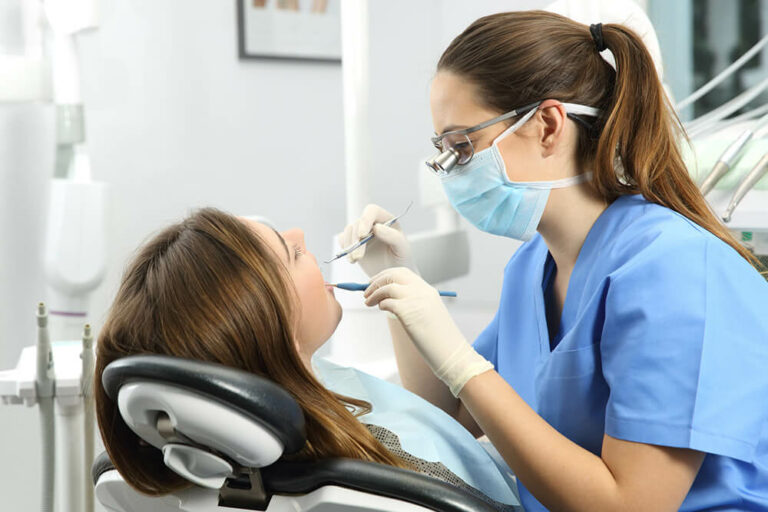 dental assistant probes a patient's gum line to identify gum disease