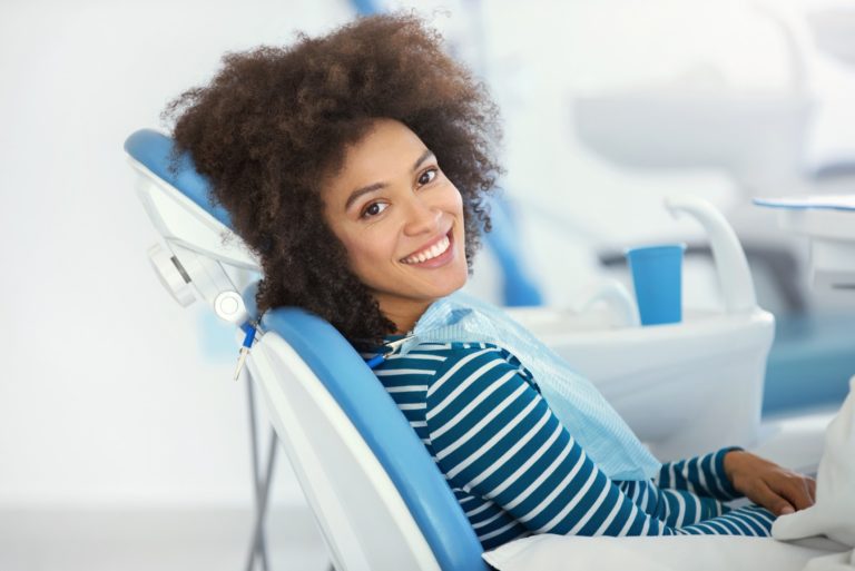 woman sitting in dental chair looking at camera and smiling