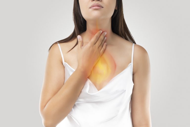 Portrait of a woman holding her hand on her throat, indicating that it is burning