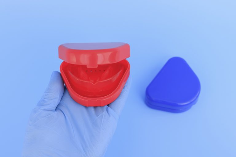 Doctor's hand, holding a mouth guard container