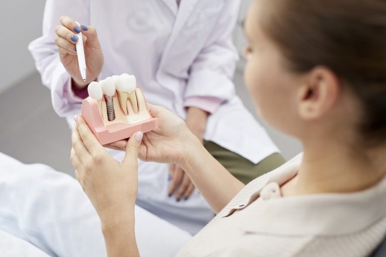 Dental patient holding a tooth implant model