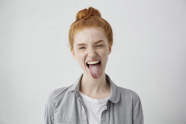 Young female with red hair, sticking tongue out with one eye closed