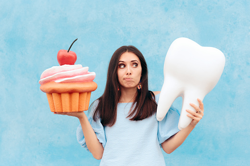 woman holding a model tooth and cupcake